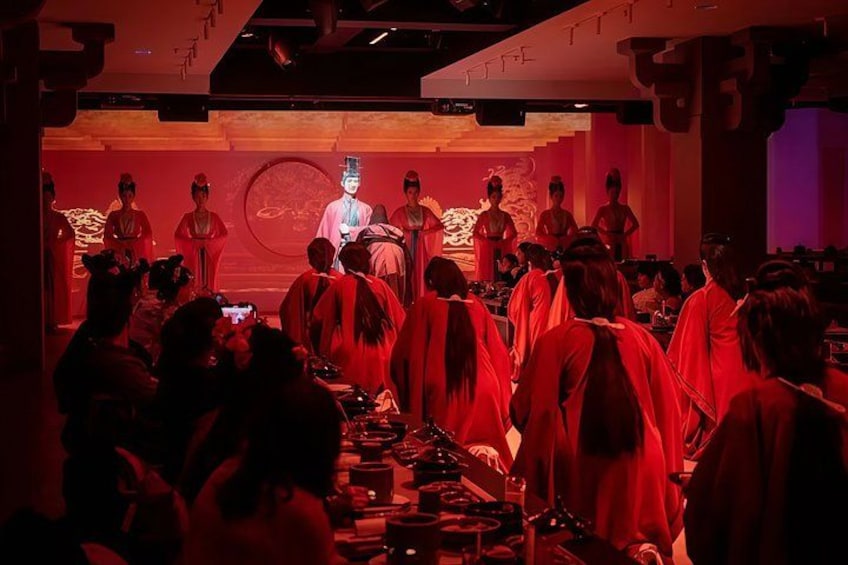 A group of people in traditional attire, gathered in a dimly lit room with red lighting. 1