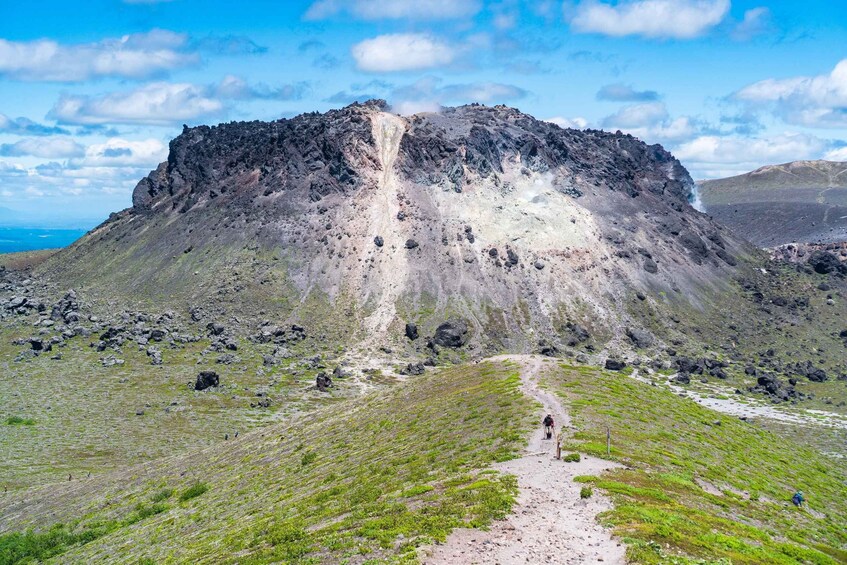 A mountain with a steep, rocky face and a narrow path leading up to it. 1