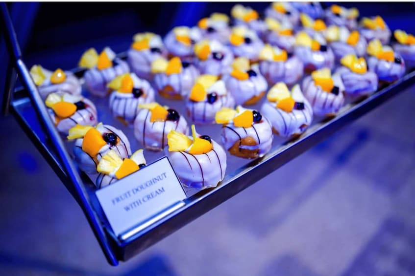 A display of white chocolate desserts with orange and yellow fruit toppings, labeled as 'Fruit Origin White Cream'. 1