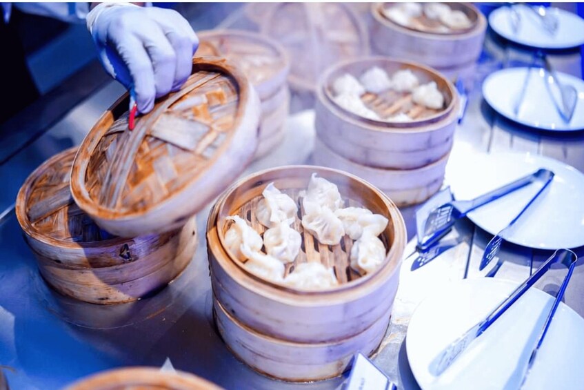 A person handling bamboo steamers with dumplings. 2