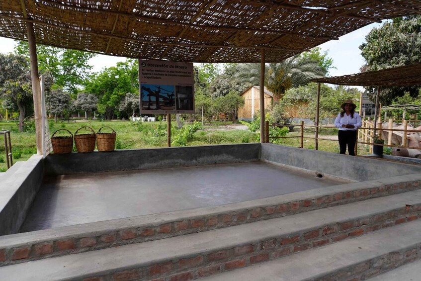 A traditional stone mortar with a sign, surrounded by a covered area with steps and baskets. 5