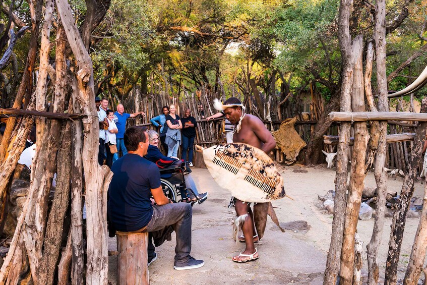 A group of people in a forested area with a person playing a traditional stringed instrument. 3