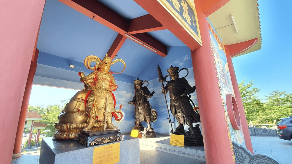 A shrine with golden and black statues of deities, surrounded by a red and blue structure. 2