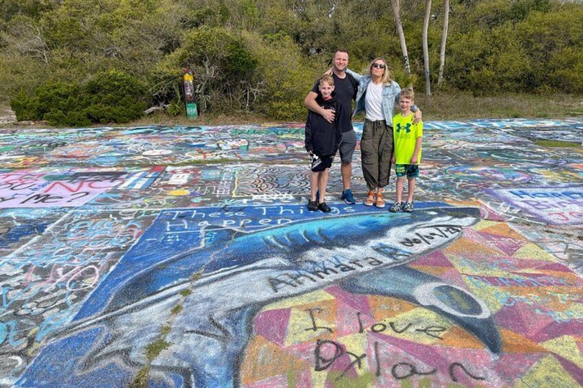 A large chalk drawing on the ground with people standing in front of it. 3