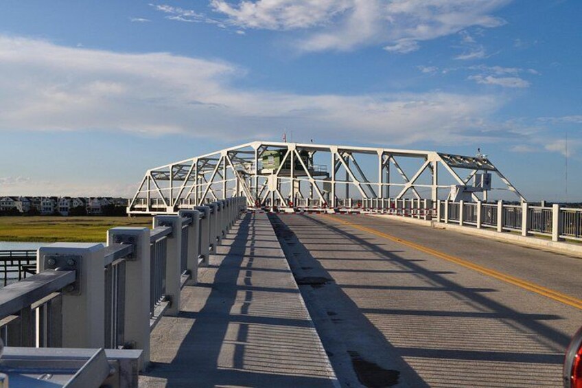 A metal bridge with a pedestrian walkway, railings, and a clear sky. 2
