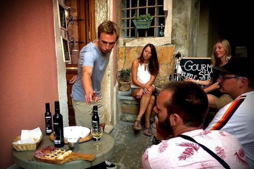 A man serving wine to guests at a table with a sign reading "Gourmet Purple Shop". 2