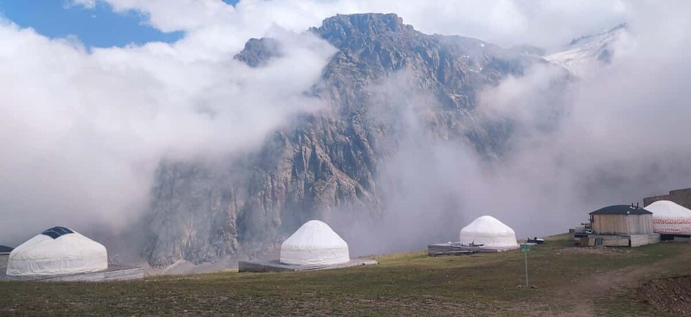 Yurts in a grassy field with a mountain in the background. 4
