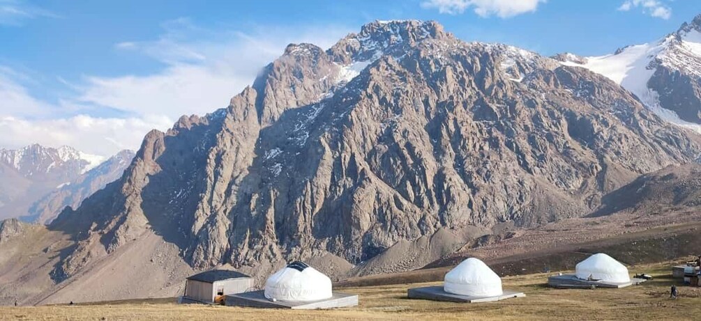 A mountainous landscape with yurts and a clear sky. 2