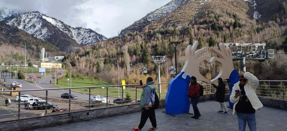 A mountainous landscape with a ski lift, a road with cars, and people walking. 5