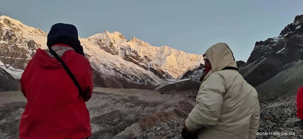 Two people in outdoor jackets observing a mountainous landscape. 2