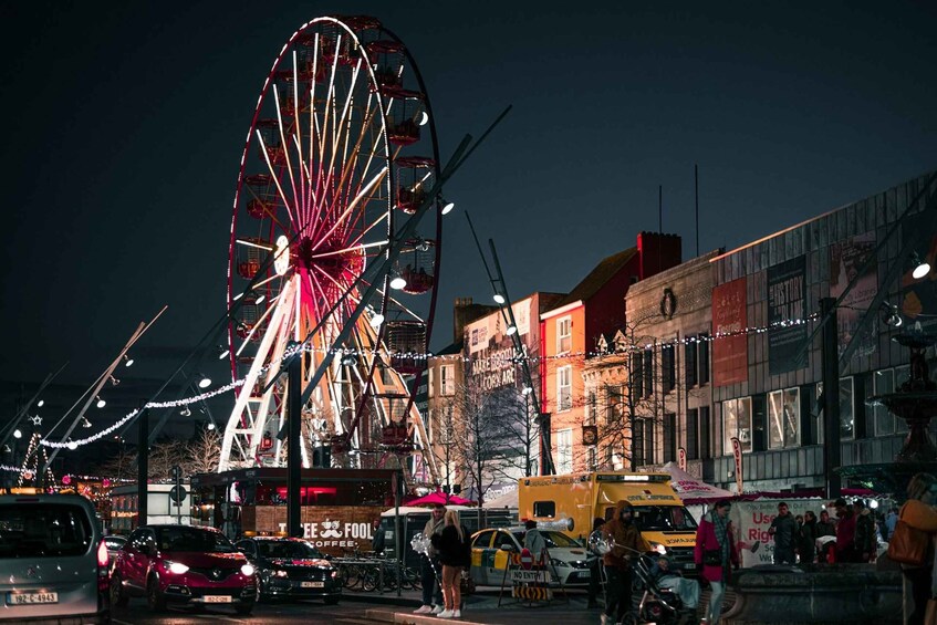 A Ferris wheel at night with a coffee cart and a yellow taxi in the foreground. 5