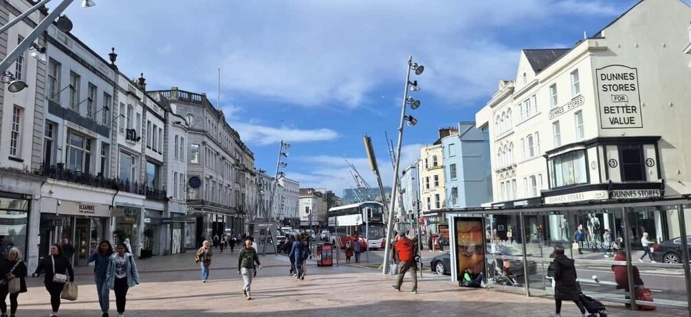 A busy urban street with pedestrians, shops, and a bus stop. 2