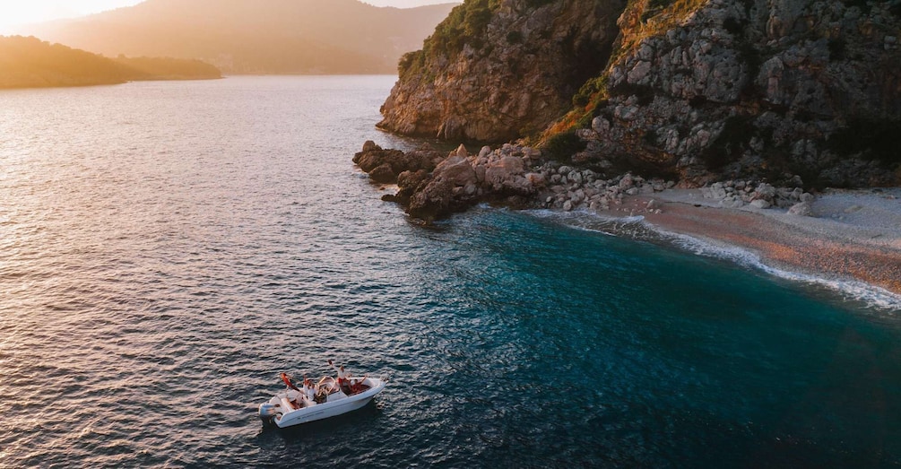 A boat on a turquoise sea near a rocky coastline with a beach. 5