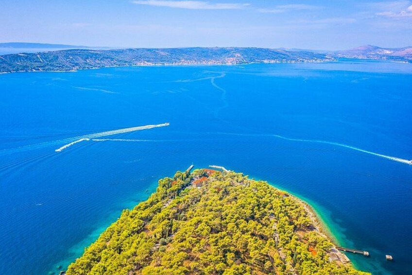 Paesaggio costiero con un'isola boscosa e acque blu cristalline. 1
