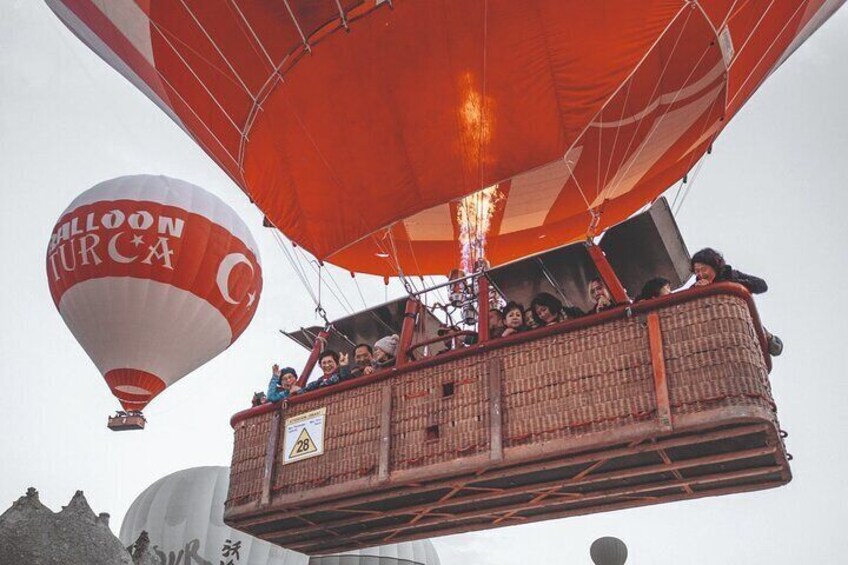 A hot air balloon with passengers, a basket, and a large building in the background. 5