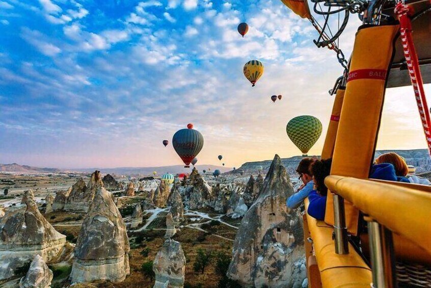 A landscape with unique rock formations and hot air balloons in the sky. 3