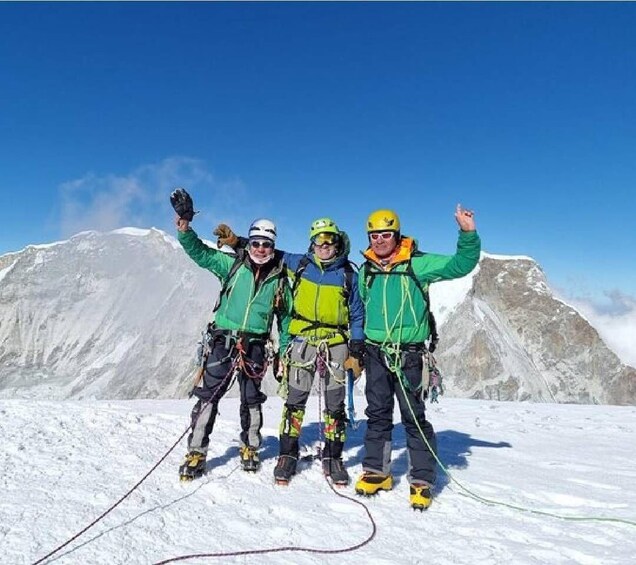 Four climbers on a snowy mountain peak with their arms raised. 3