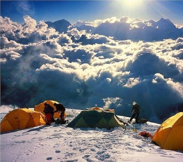A snowy mountain with tents and a person climbing. 1