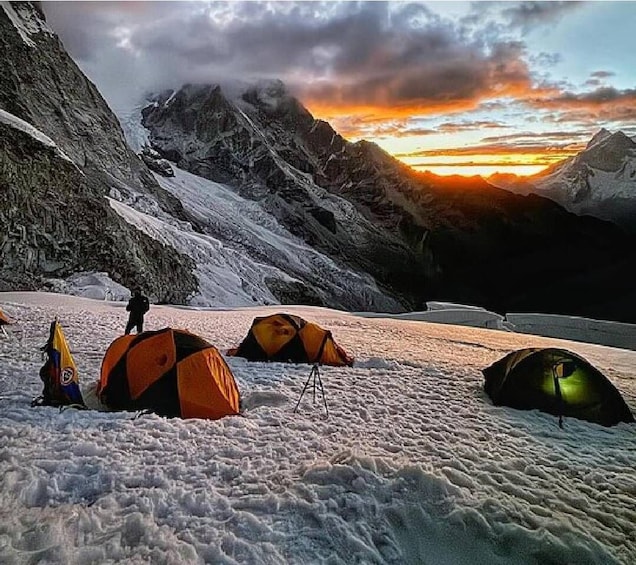 A snowy mountain landscape with tents and a person standing. 2