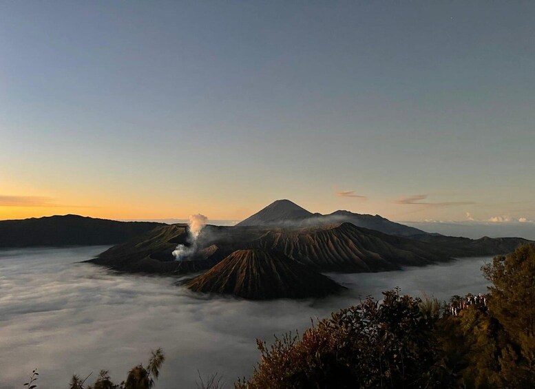 A volcanic landscape with multiple craters and smoke rising from one. 2