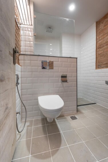 A modern bathroom with a glass-enclosed shower, white tiles, and a wooden accent wall. 4