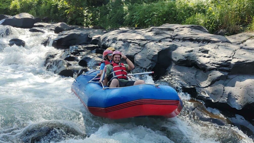 Two people in a blue and red raft navigating a river with rapids. 5