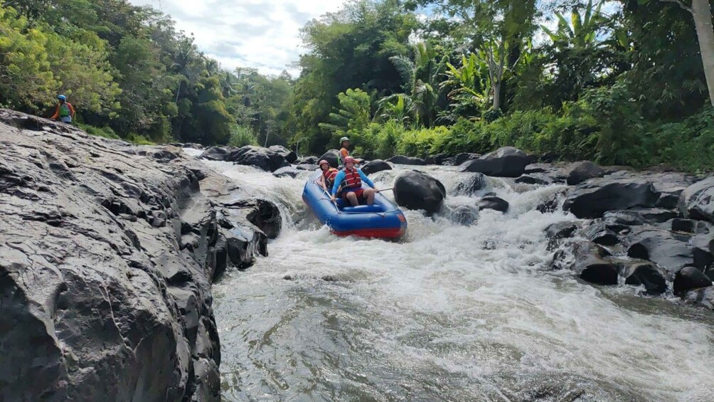 A person rafting down a river surrounded by rocks and greenery. 2