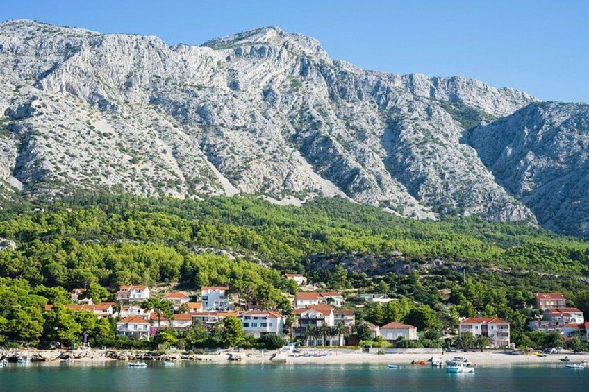A coastal town with houses, a beach, and mountains in the background. 1
