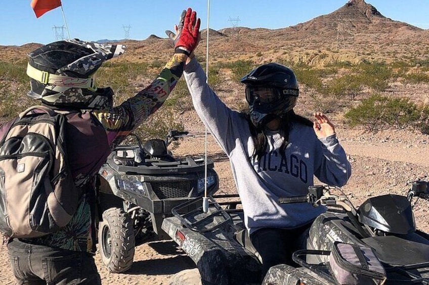 Two people on ATVs in a desert landscape with a mountain in the background. 2