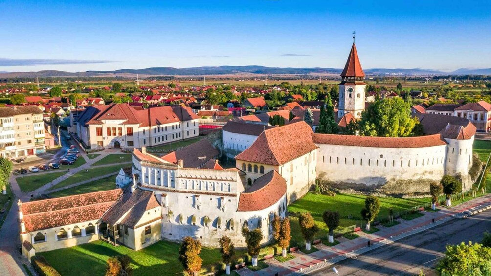 A historic town with a prominent castle, a church with a tall spire, and surrounding residential buildings. 4