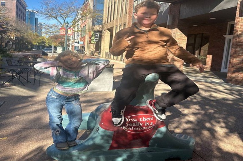 Two children playing on a colorful sculpture with text. 1