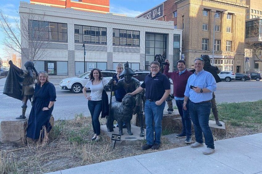 A group of people standing in front of a sculpture of a horse and rider. 4