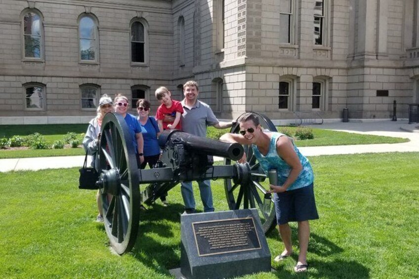 A group of people around a cannon in front of a large building. 2