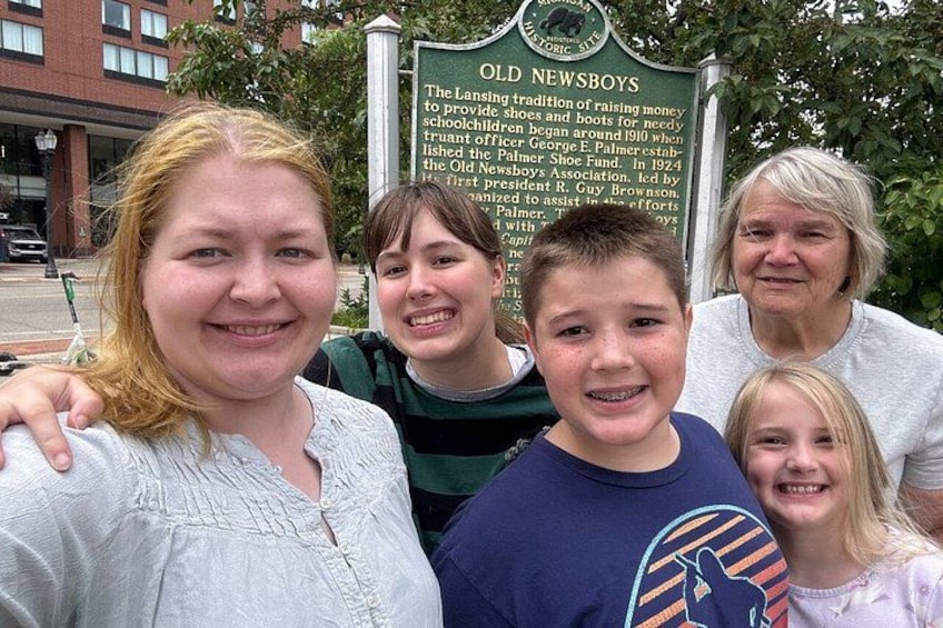 A group of people standing in front of a historical sign. 2