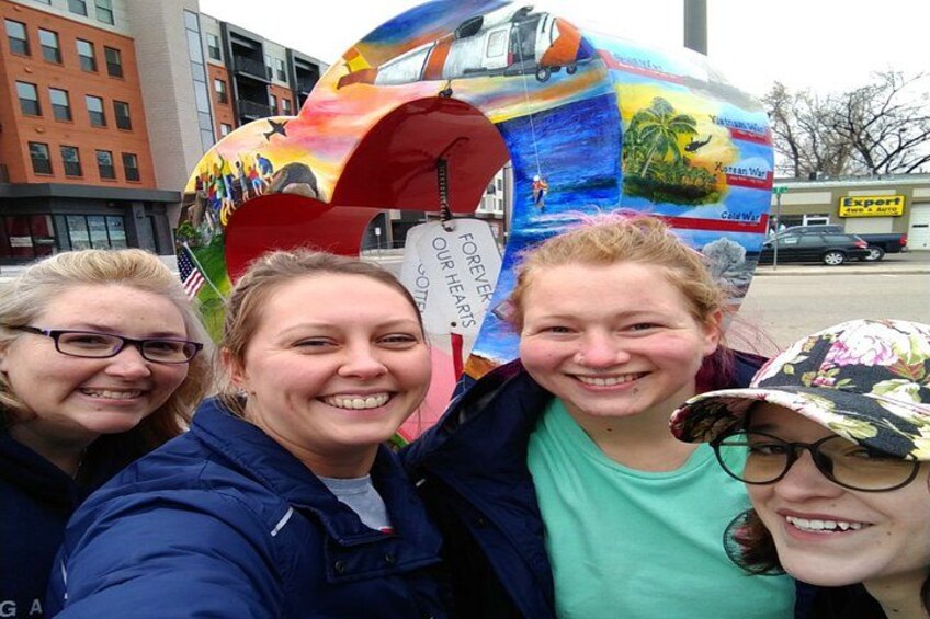 Three people taking a selfie with a colorful bus in the background. 2