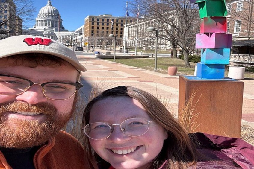 A person wearing a cap with a logo, a building with a dome, and a colorful sculpture. 2