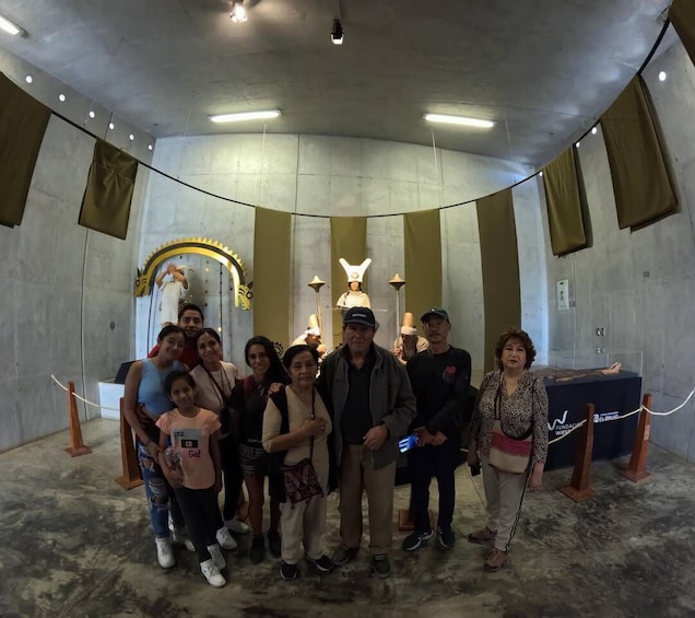 A group of people posing in a room with a curved ceiling and a statue in the background. 1