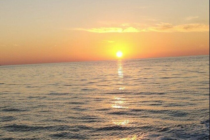 A sunset over a calm sea with a visible sun reflection on the water. 3