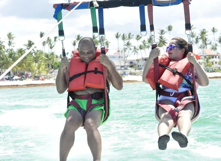 Two people on a swing ride over water with palm trees in the background. 5