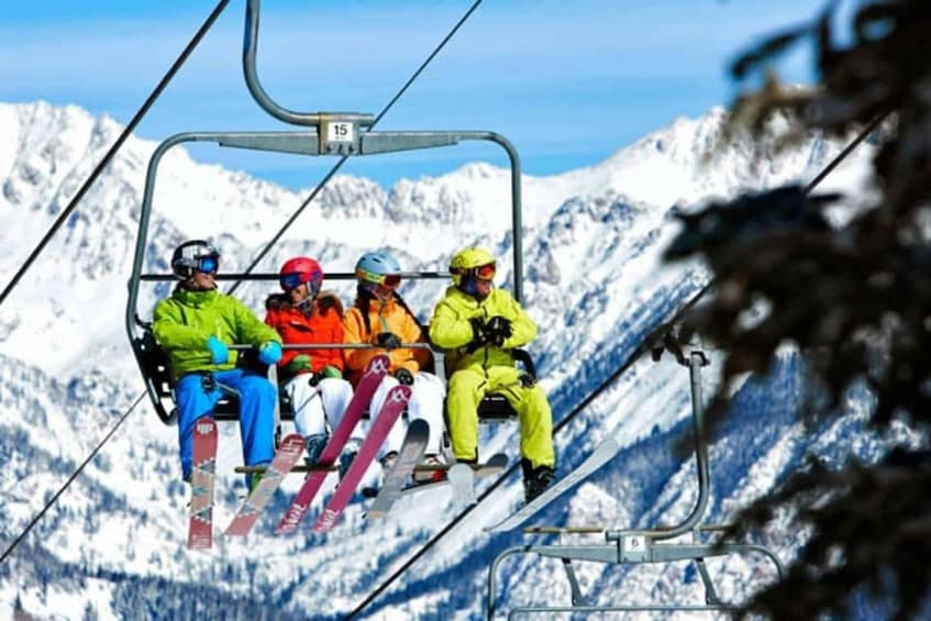 Four people on a ski lift with snow-covered mountains in the background. 5