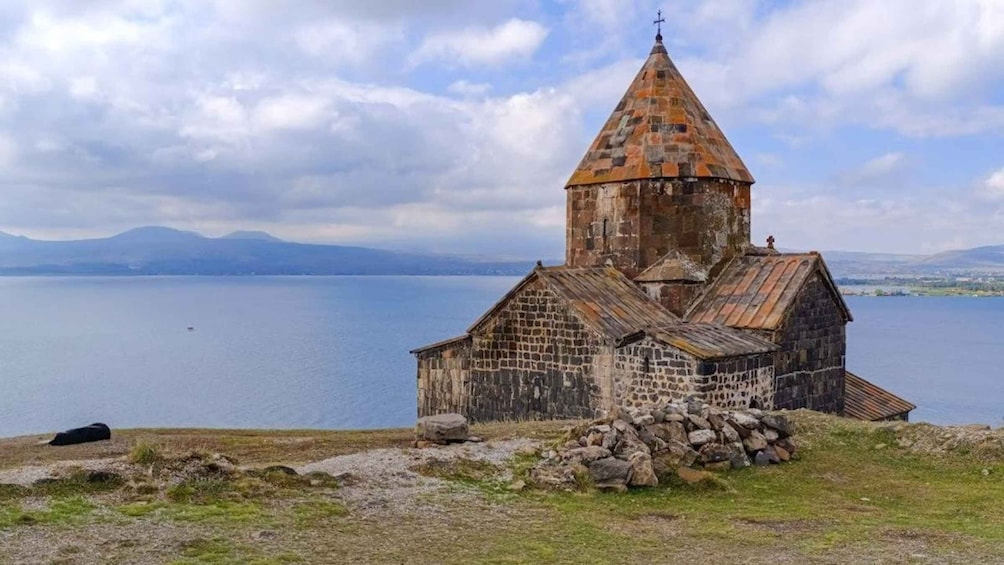A stone church with a conical roof by a lake. 4