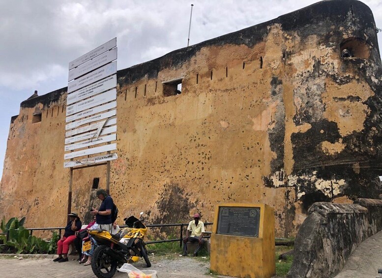 A weathered building with peeling paint and a signboard listing various job titles. 5
