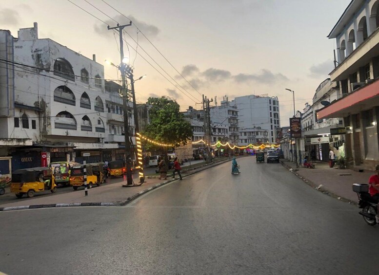 A street with buildings, vehicles, and decorative lights. 4