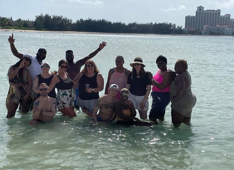 A group of people standing in shallow water near a beach with a hotel in the background. 3
