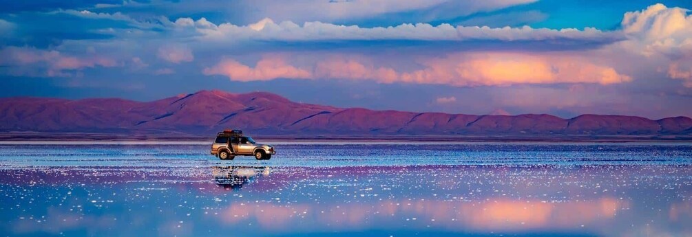 A vehicle on a reflective water surface with mountains in the background. 1