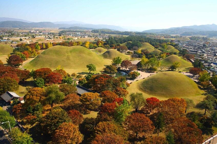 A landscape with rolling hills, autumn-colored trees, and traditional buildings. 5