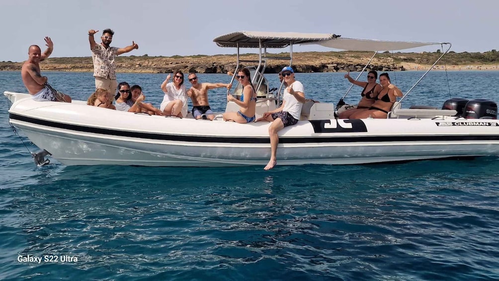 A group of people on a white motorboat with a canopy, sailing on clear blue waters. 1
