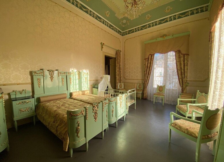 A room with a large bed, two nightstands, a chair, and a window with curtains. 2