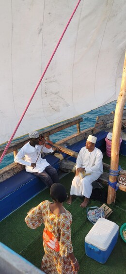 A traditional boat with passengers wearing white attire, a pink rope, and a child in a patterned dress. 2