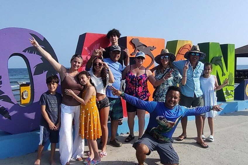Un grupo de personas posando frente a murales coloridos con temática tropical. 2